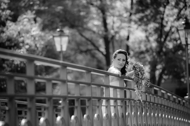 Braut lehnt über ein geschmiedetes Geländer und lächelt