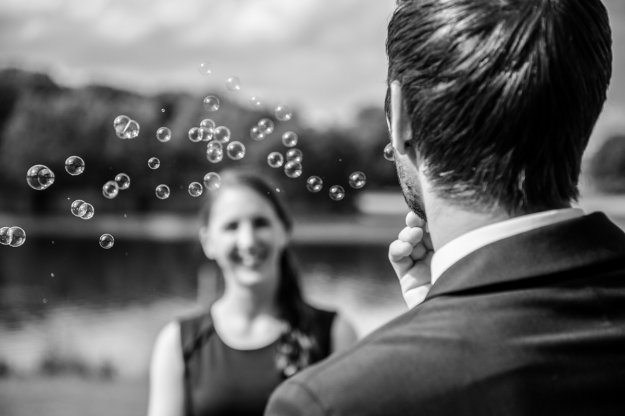 Frau Lächelt jungen Mann an der Seifenblasen pustet