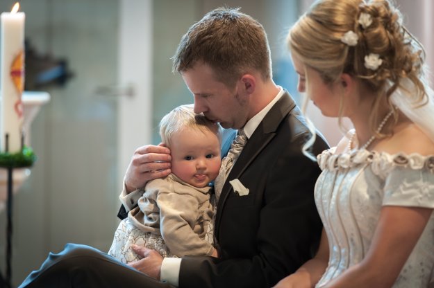 Hochzeitspaar sitzt mir ihrem Kind am Altar