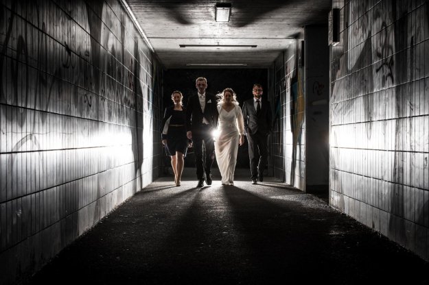 Brautpaar und Trauzeugen gehen durch einen Graffiti- Tunnel
