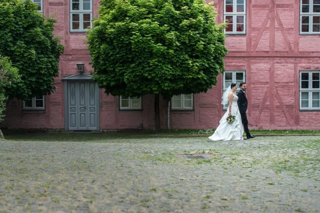 Brautpaar geht über den Platz eines Bauernhofes