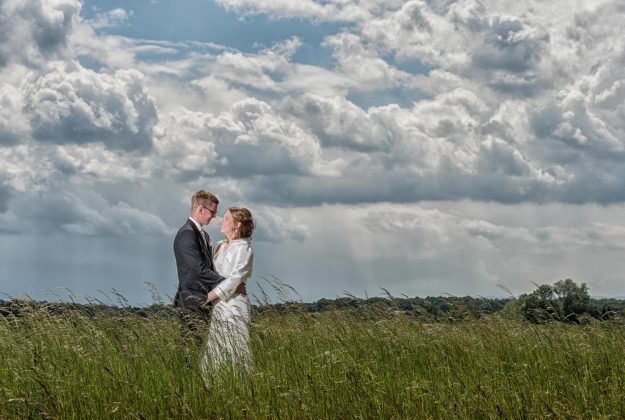 Brautpaar steht im Feld und umarmt sich